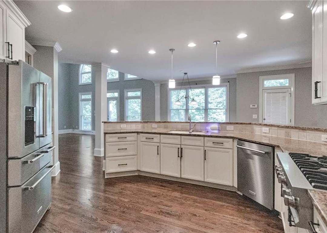 Chef's kitchen with white cabinetry, granite counters, a stainless French-door refrigerator, a gas cooktop, and pendant lighting over the peninsula