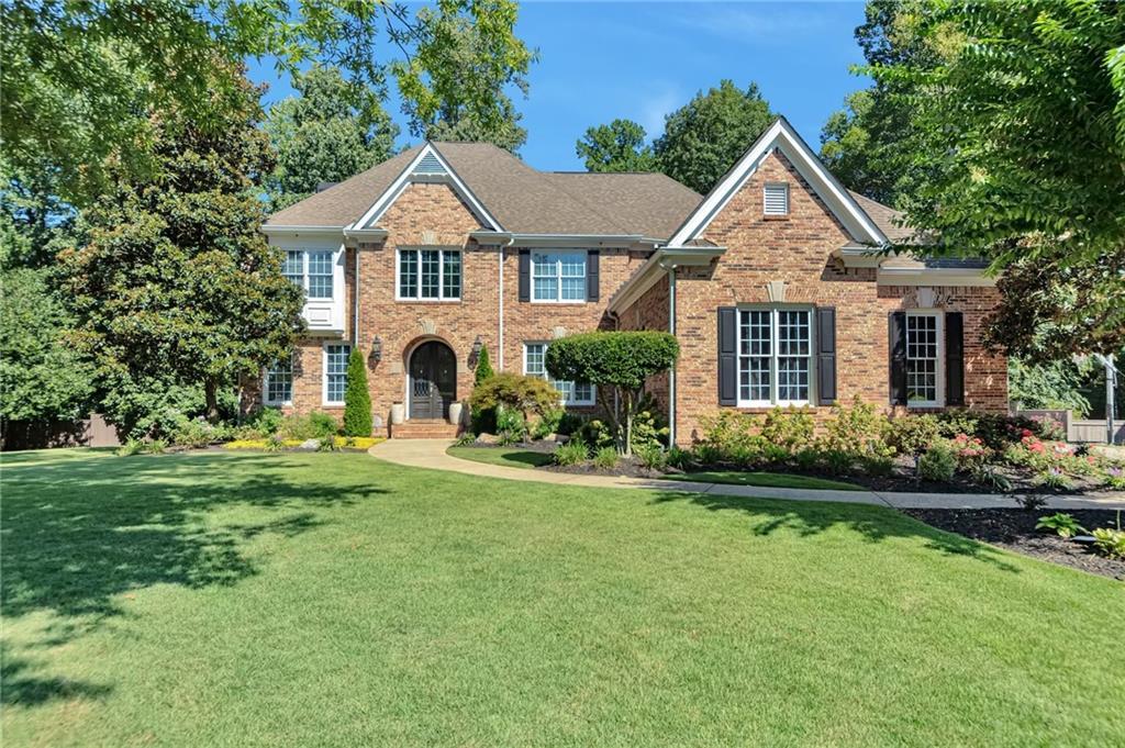 Front elevation of 1421 Castlebrooke Way, a two-story four-sided brick estate with an arched entry, shuttered windows, and a manicured front lawn in Marietta, Georgia